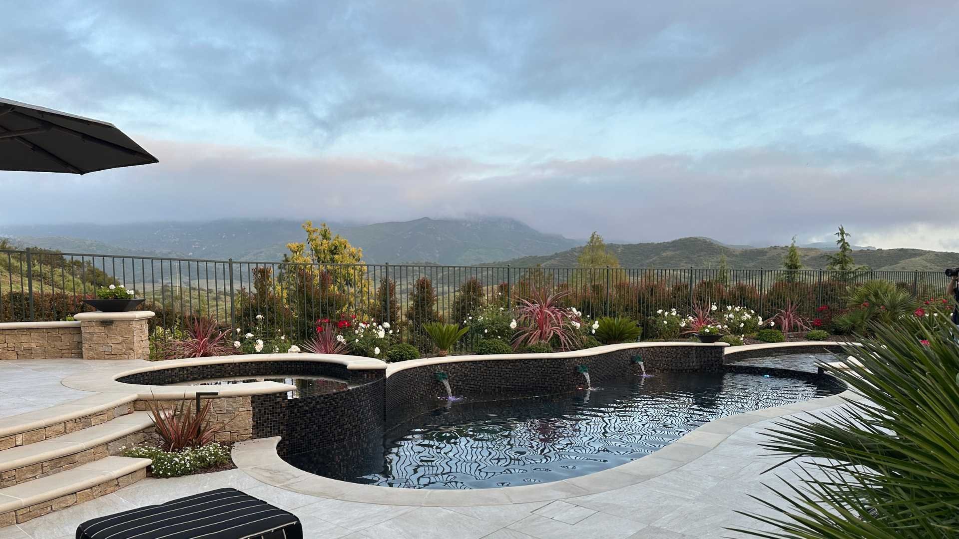 Wide shot of the pool area with a dark plaster finish, surrounded by a garden and mountain views in Thousand Oaks