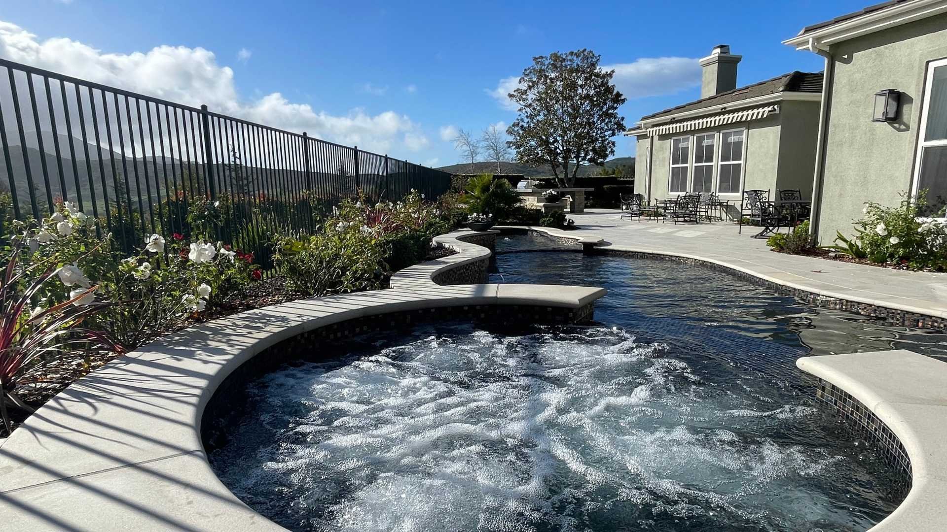 Spa with bubbling jets in action, integrated into the pool with a view of the mountains in the background.