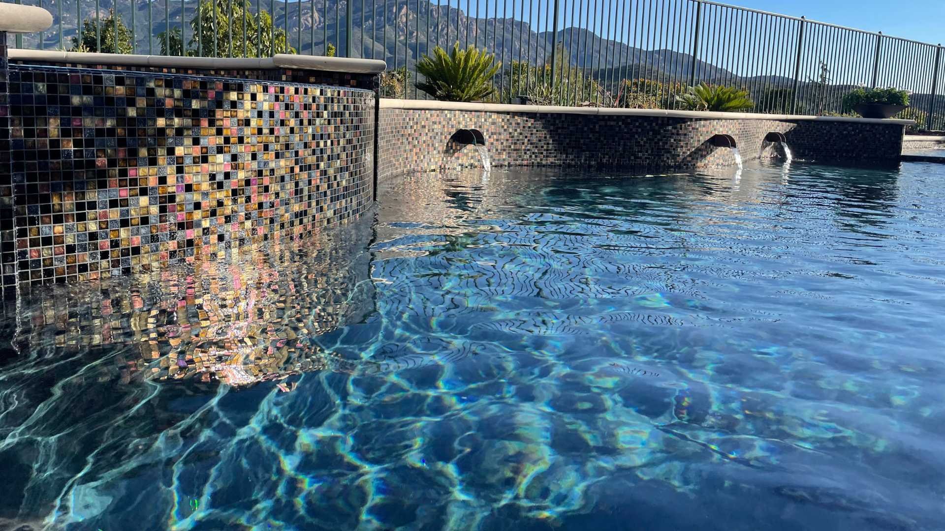 Close-up of the raised bond beam with glass tiles and copper scuppers, water cascading into the pool below.