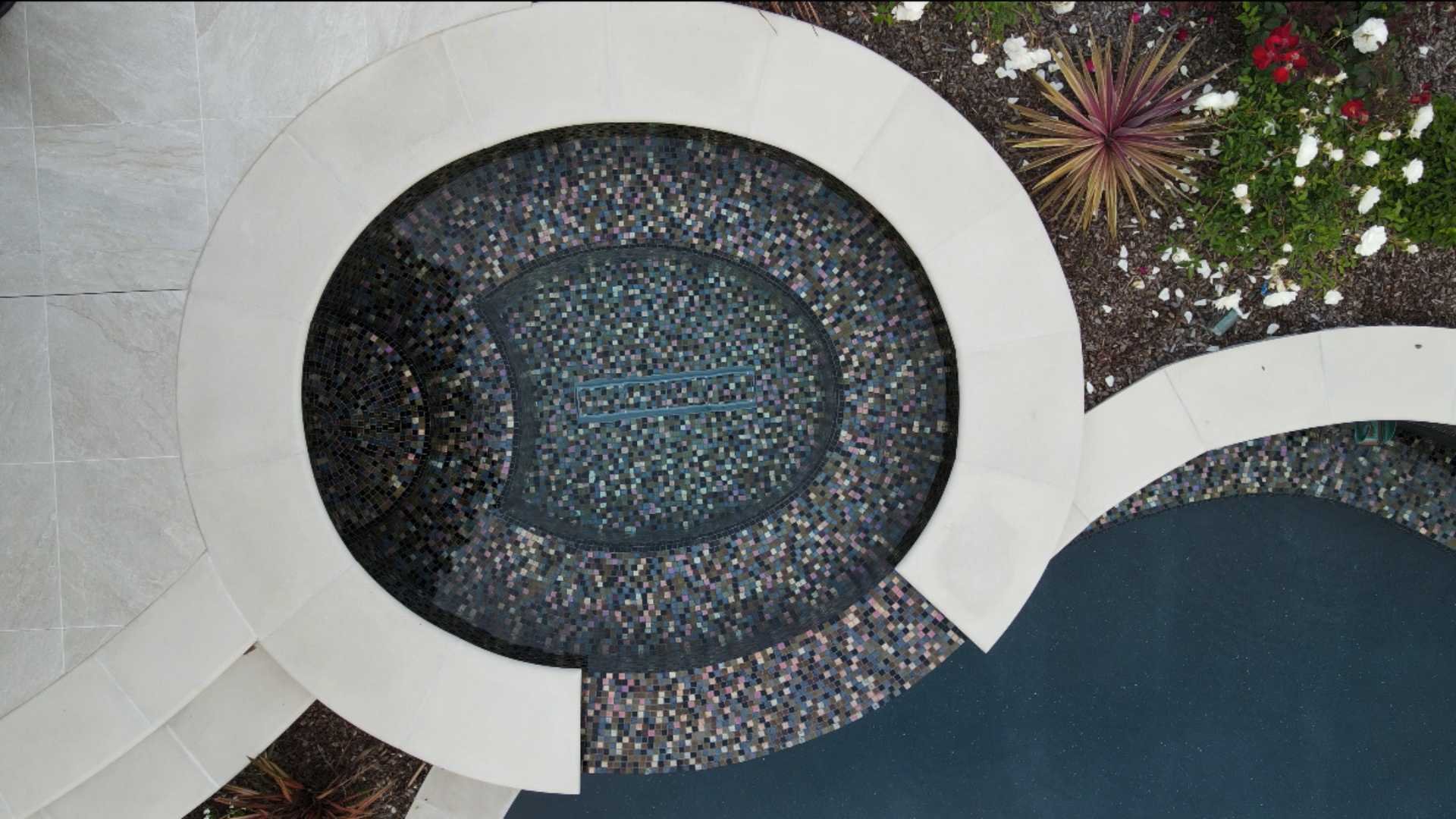 Aerial view of the spa with intricate glass tile work adjacent to the pool, highlighting its round design.