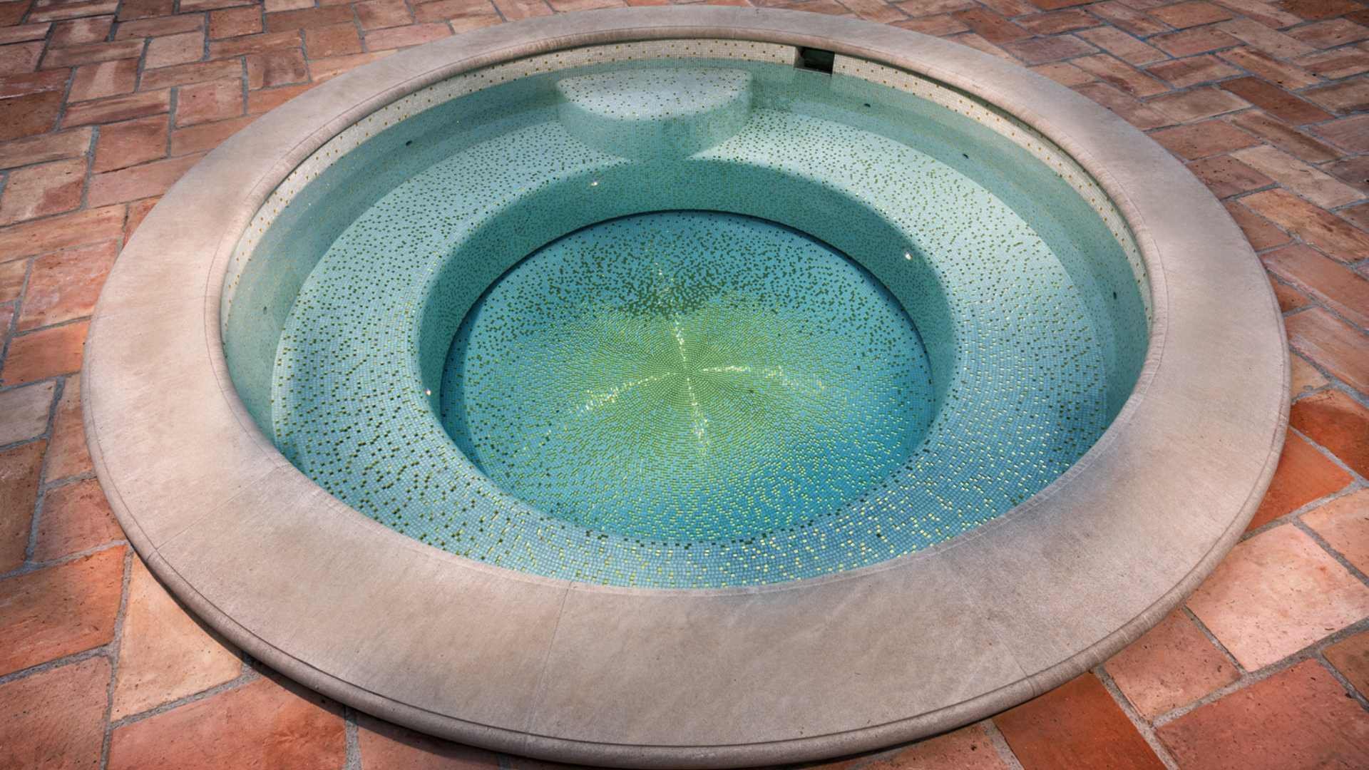 A close-up of a fully tiled spa with gold splattered tiles, set on a terracotta tile deck in Hollywood.