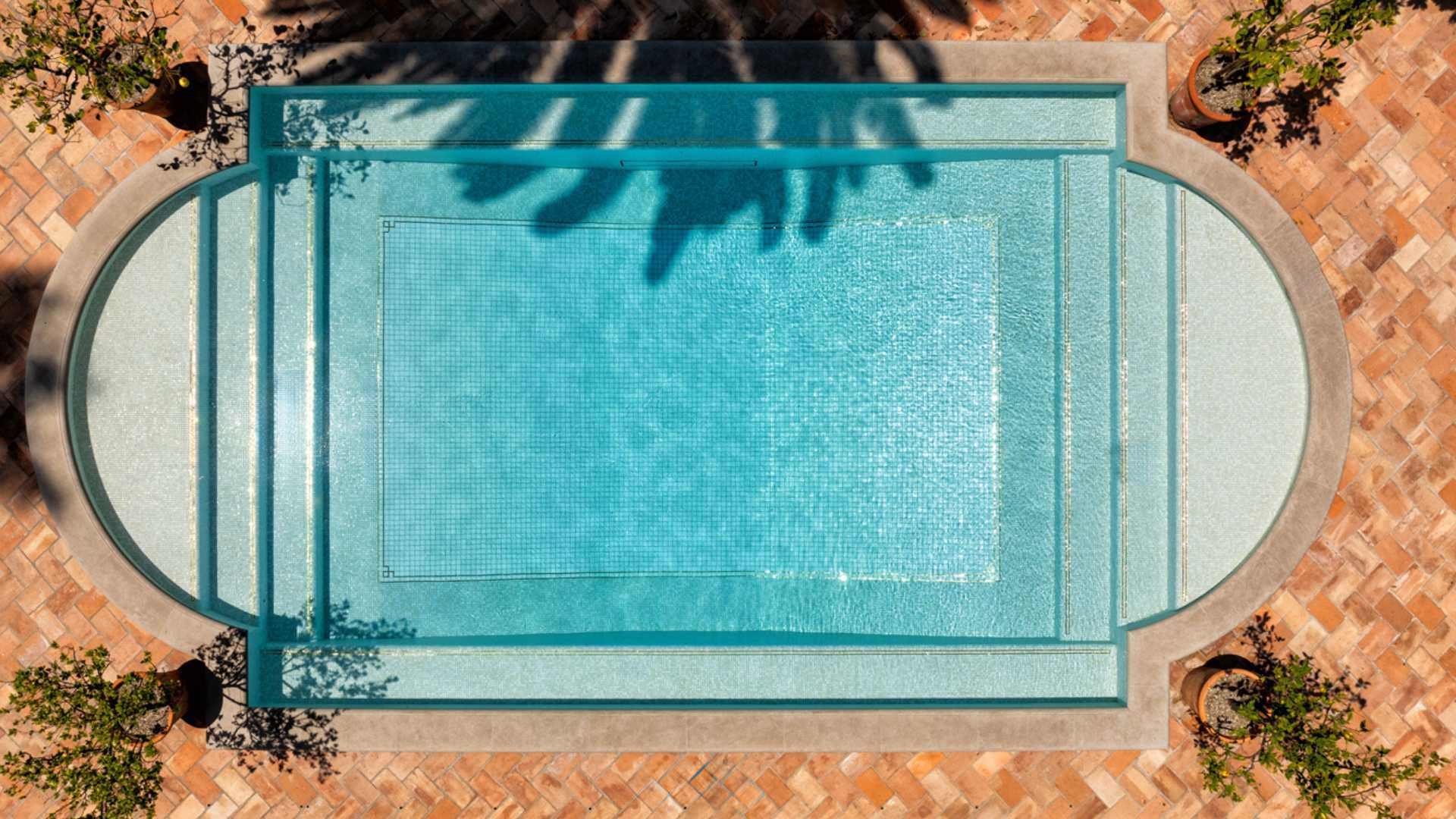 Daytime view of a fully tiled pool in Hollywood, framed by terracotta tiles and potted citrus trees, equipped with ozone sanitation.
