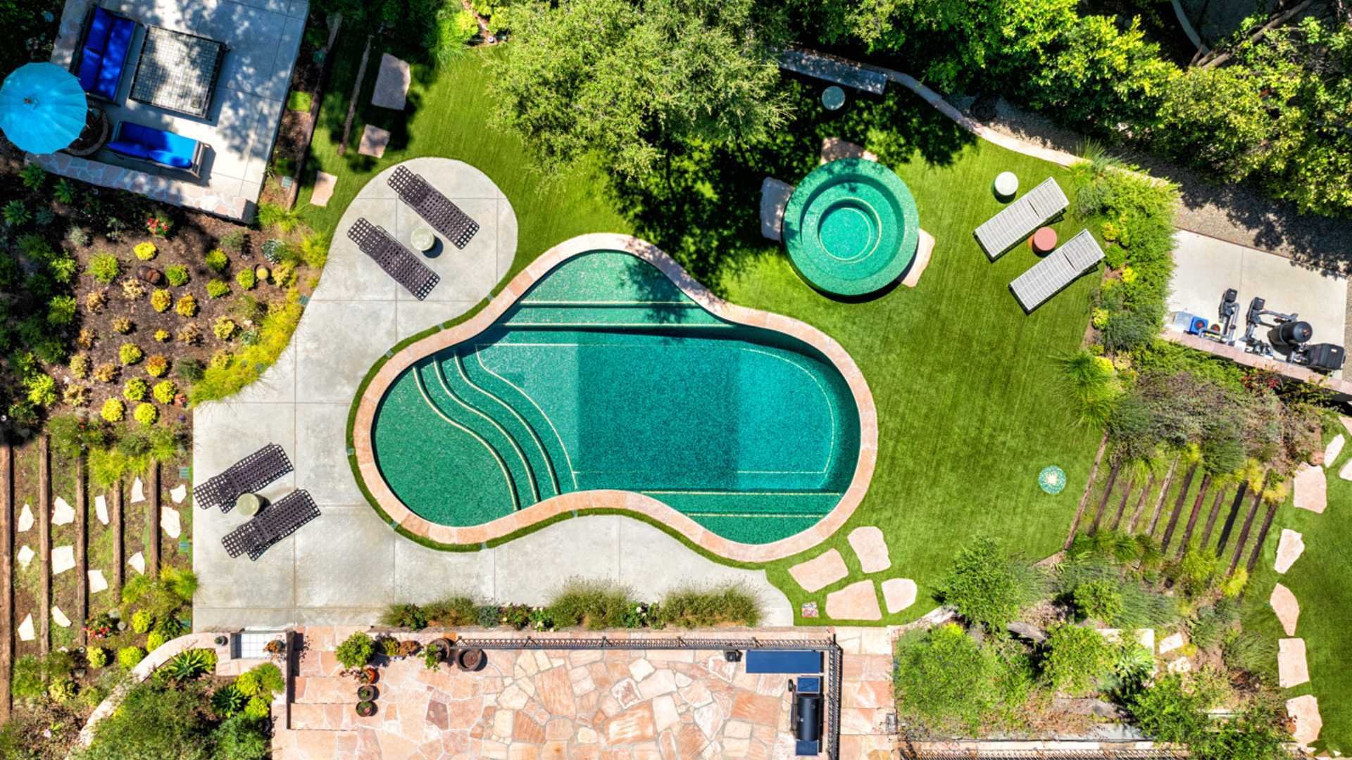 Aerial view of a Calabasas property featuring a fully tiled pool, beach entry, double set of steps, and raised round spa.