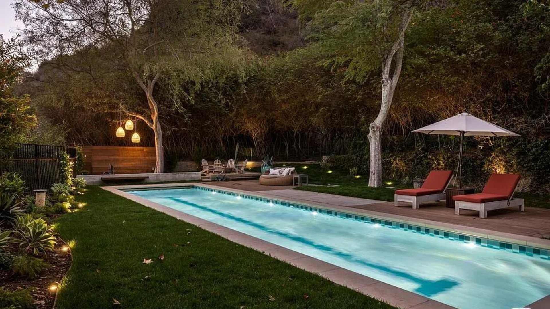 A rectangular pool with blue tile featuring a central lane marker, bordered by a green lawn, illuminated with 6 LED lights