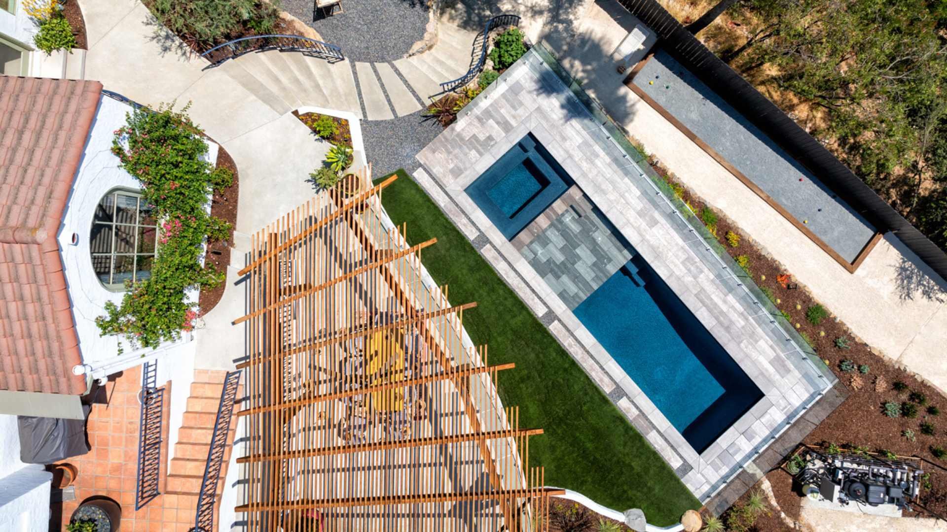 Top-down view of a sleek pool and spa with Greek marble decking in a Silver Lake backyard, bordered by a bocce ball court.