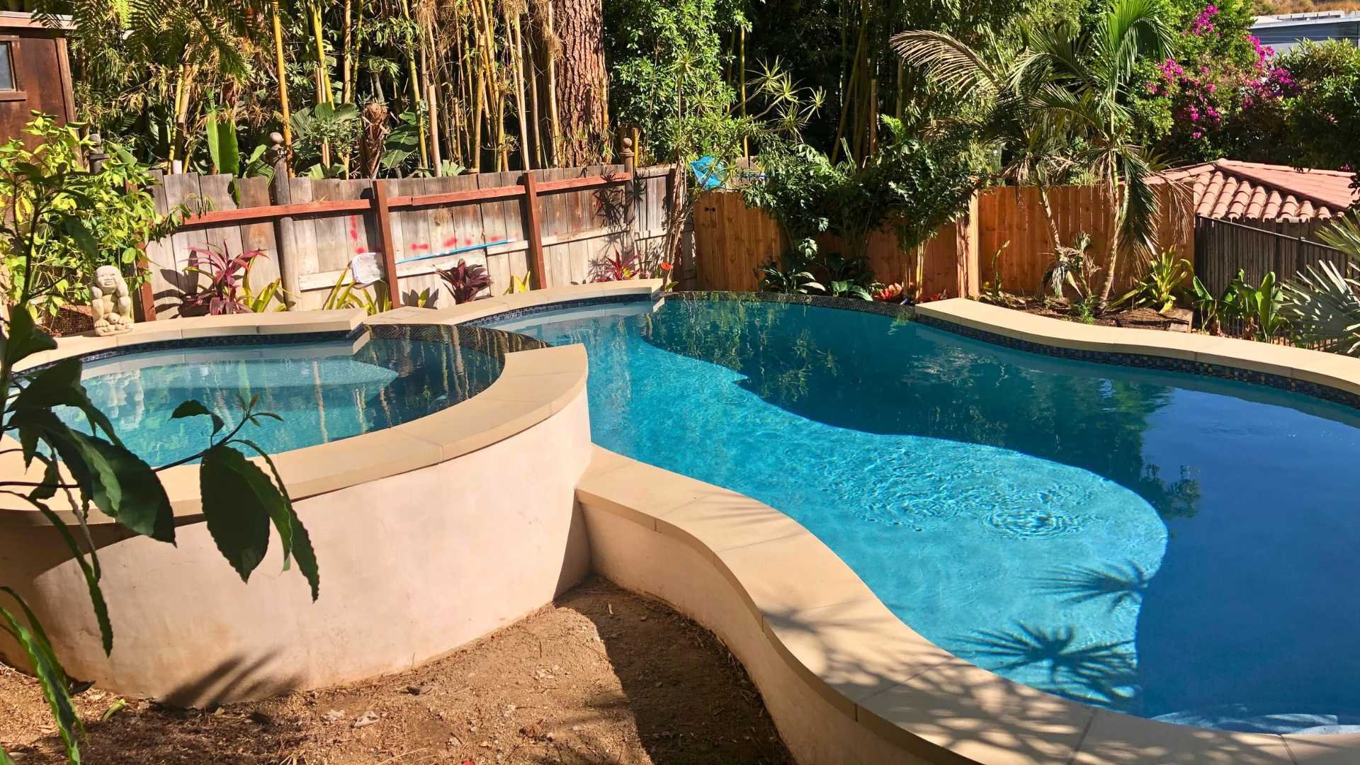 View of the pool and raised spa from a garden perspective, showcasing the natural integration with the surrounding landscape.