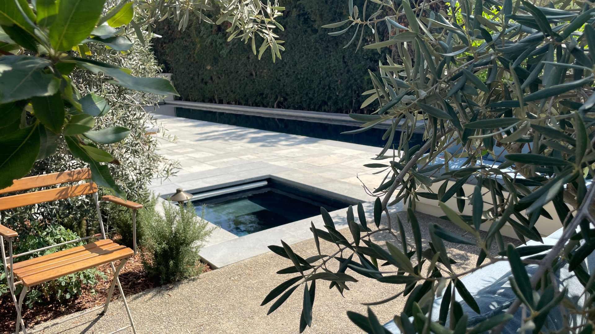 Sunken spa surrounded by greenery and a paver deck