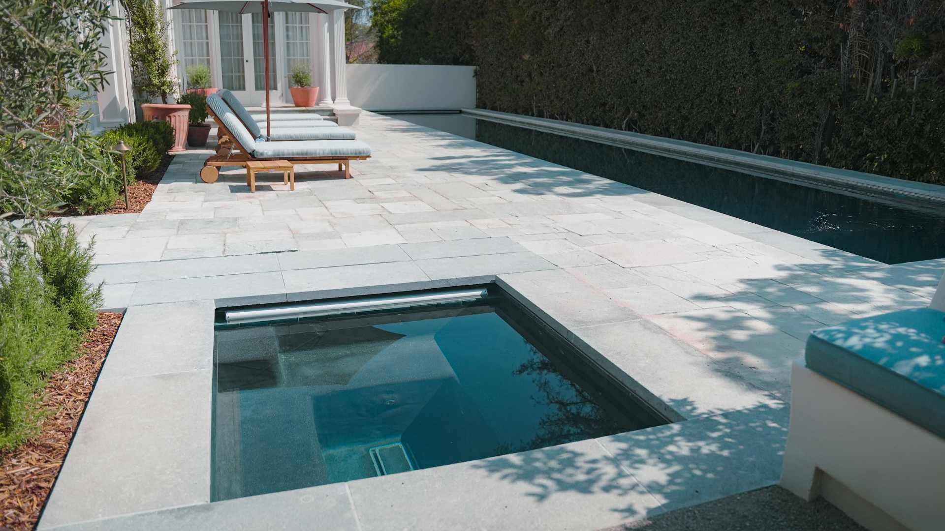 sunken spa next to a long swimming pool