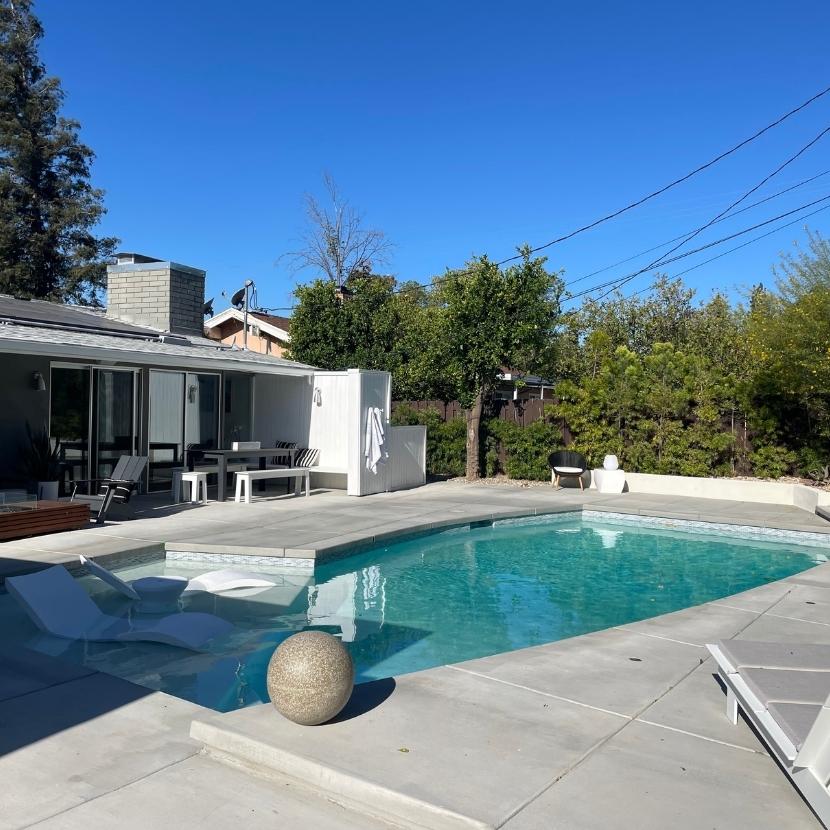 swimming pool with a tanning ledge and chairs