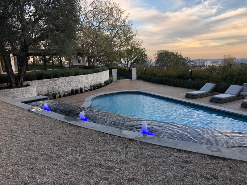 Experience luxury with JDesigns' outdoor pool, showcasing fountains & bubblers in a unique blend of traditional-modern & mid-century American styles.