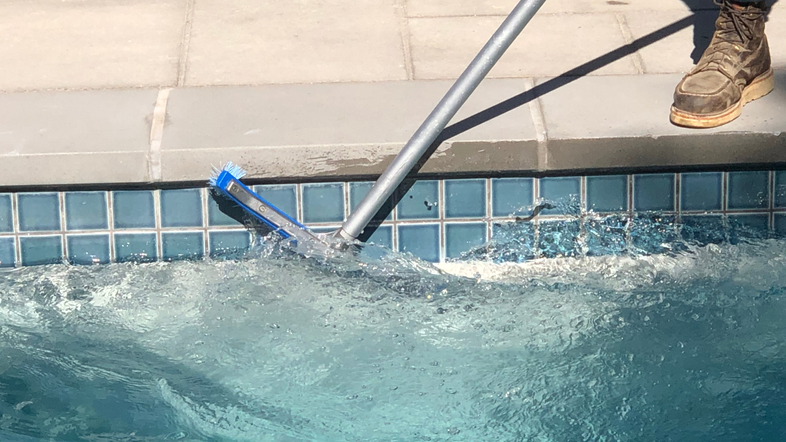 pool brushing the tile along the waterline on the inside of the pool